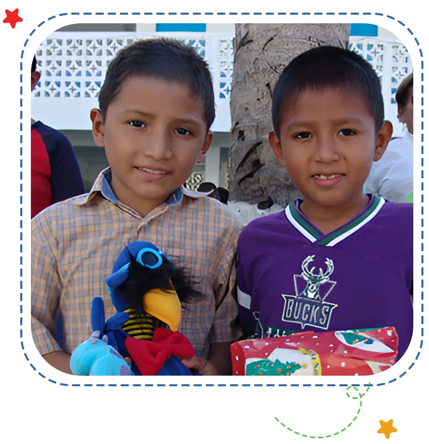 Two boys holding a parrot and wearing blue shirts.