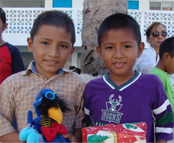 Two boys holding a stuffed animal and some presents