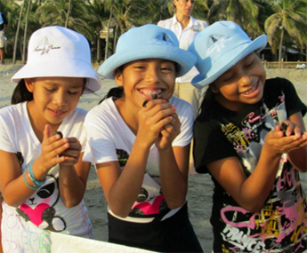 Three young girls wearing hats and eating ice cream.