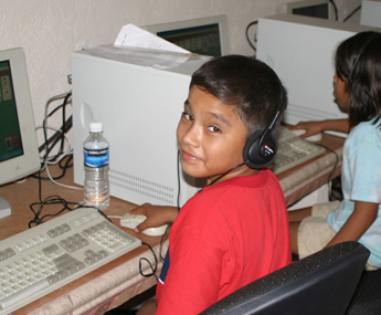 A boy wearing headphones sitting at a computer desk.