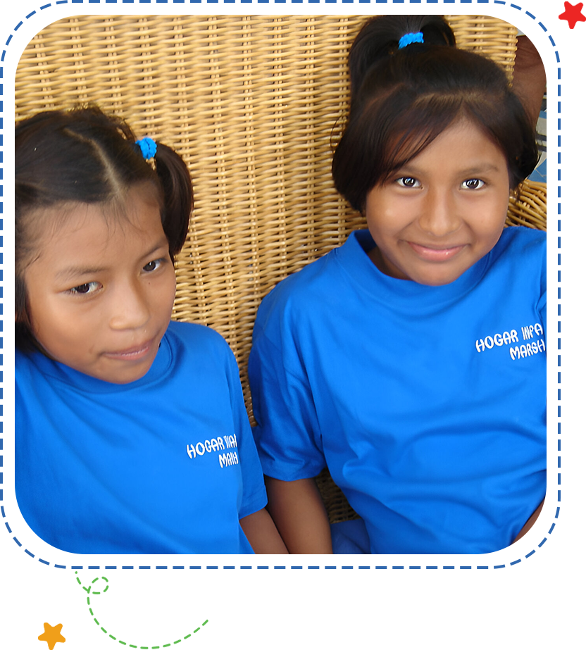 Two young girls wearing blue shirts and smiling.