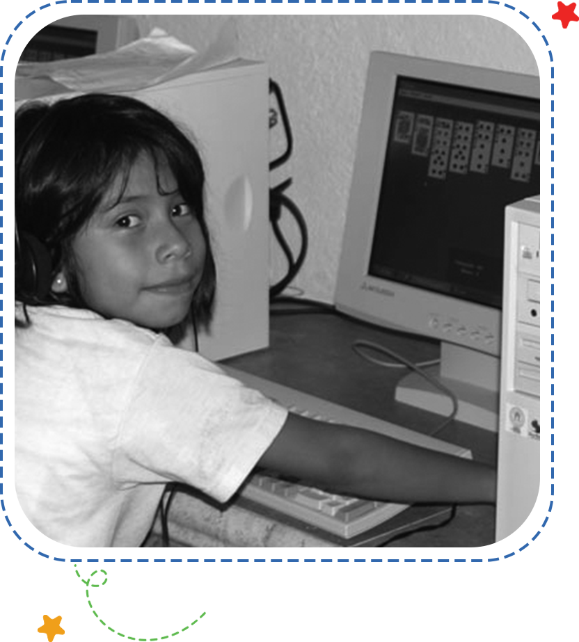 A young girl sitting at the computer desk.