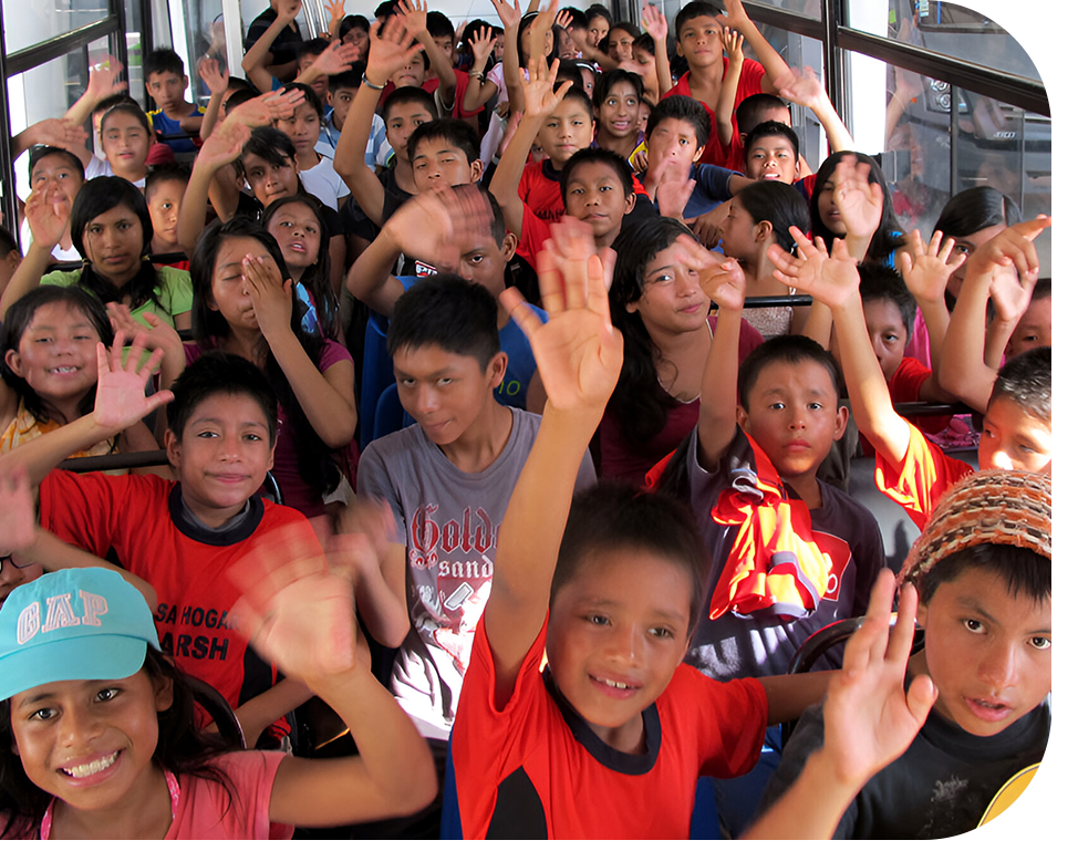 A group of children in red shirts waving.